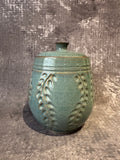 Handcrafted  blue ceramic lidded canister with carved leaf patterns on surface.