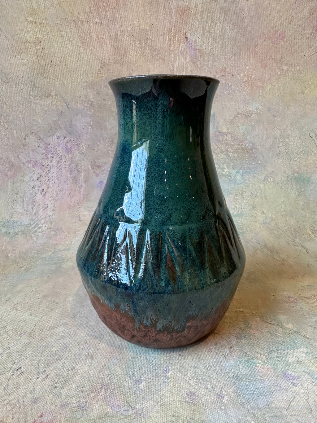 A handmade ceramic vase with a glossy dark green and copper glaze, featuring a flared rim and carved texture surface.