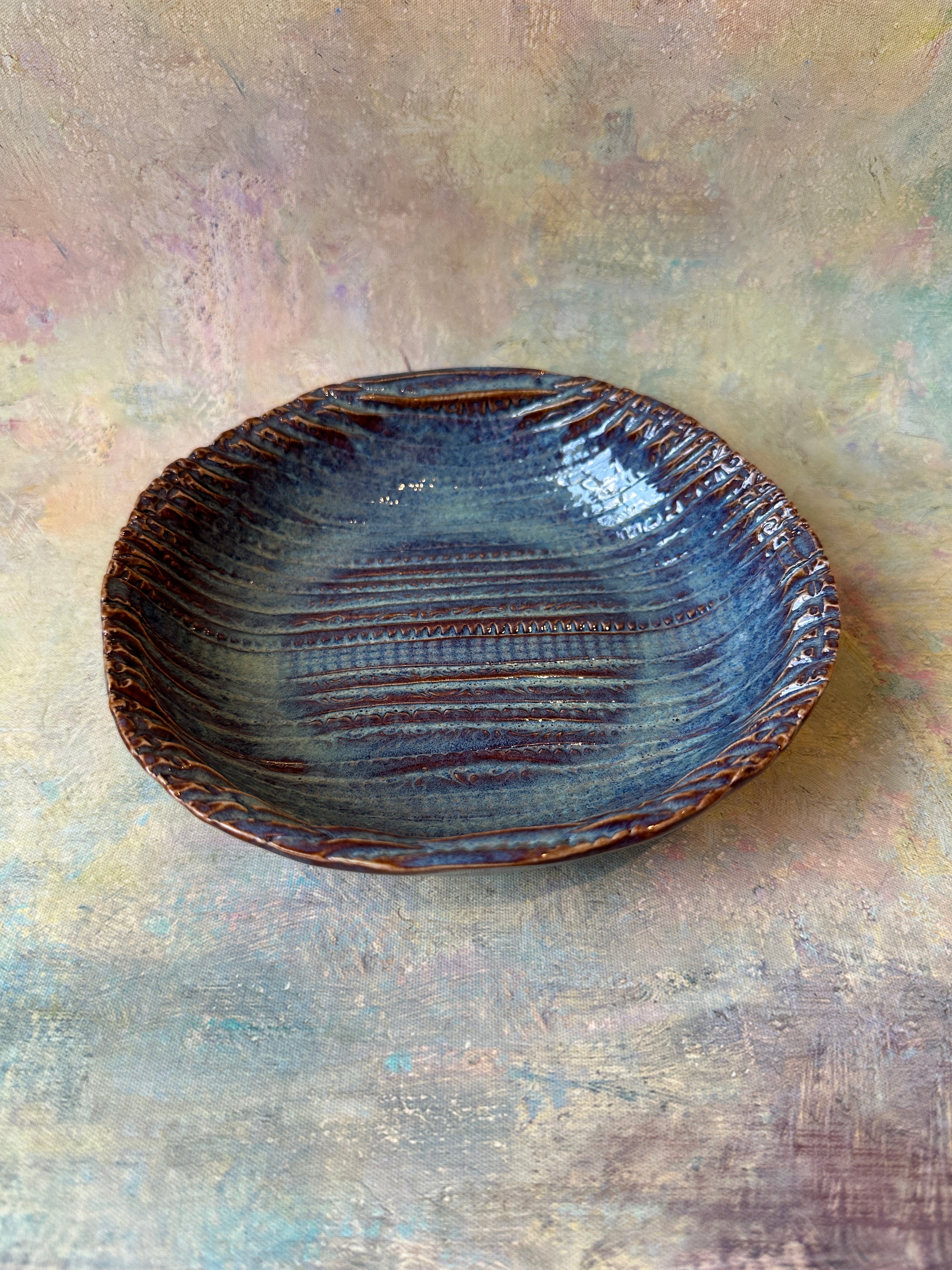 A handcrafted stoneware bowl with a textured, ribbed interior and a glossy, denim blue glazed interior, shown from a top-down view.
