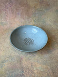 A handmade ceramic garlic grater bread dipping oil bowl with a light robins egg blue glaze and a textured floral center for garlic grating.