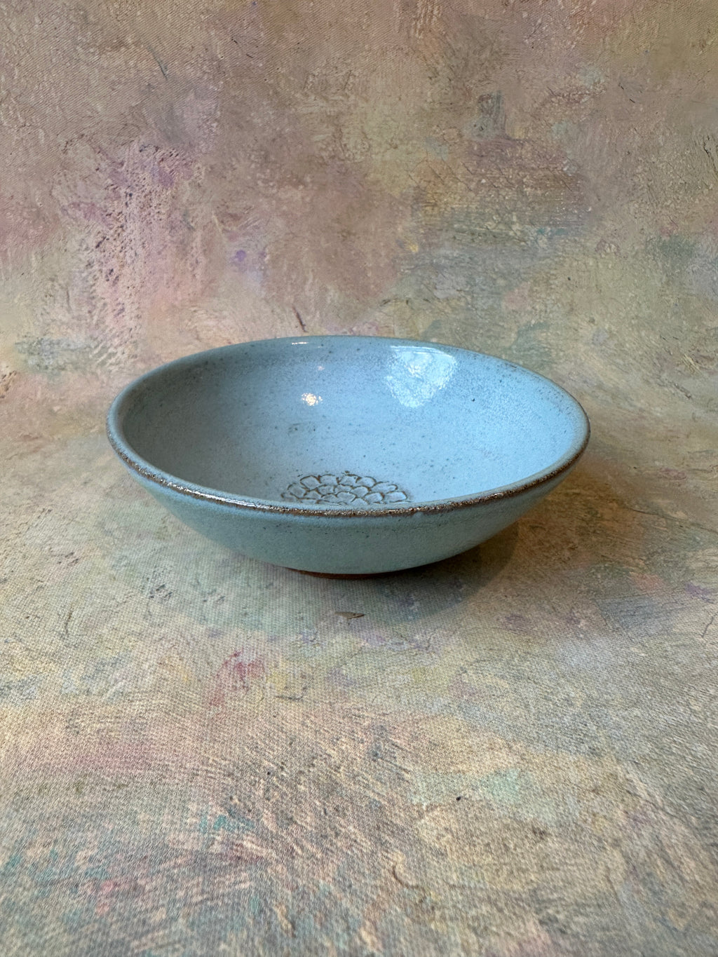Wheel thrown stoneware ceramic garlic grater bread dipping oil bowl with a light robins egg blue glaze and a textured floral center for garlic grating.