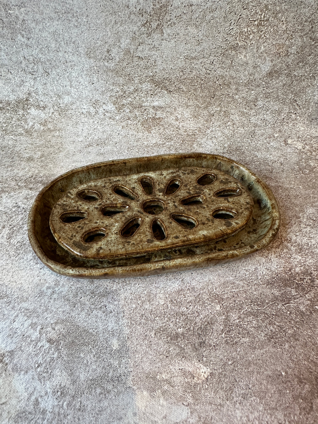 An oval ceramic 2pc soap dish with a decorative cutout pattern to allow your bar soap to drain.